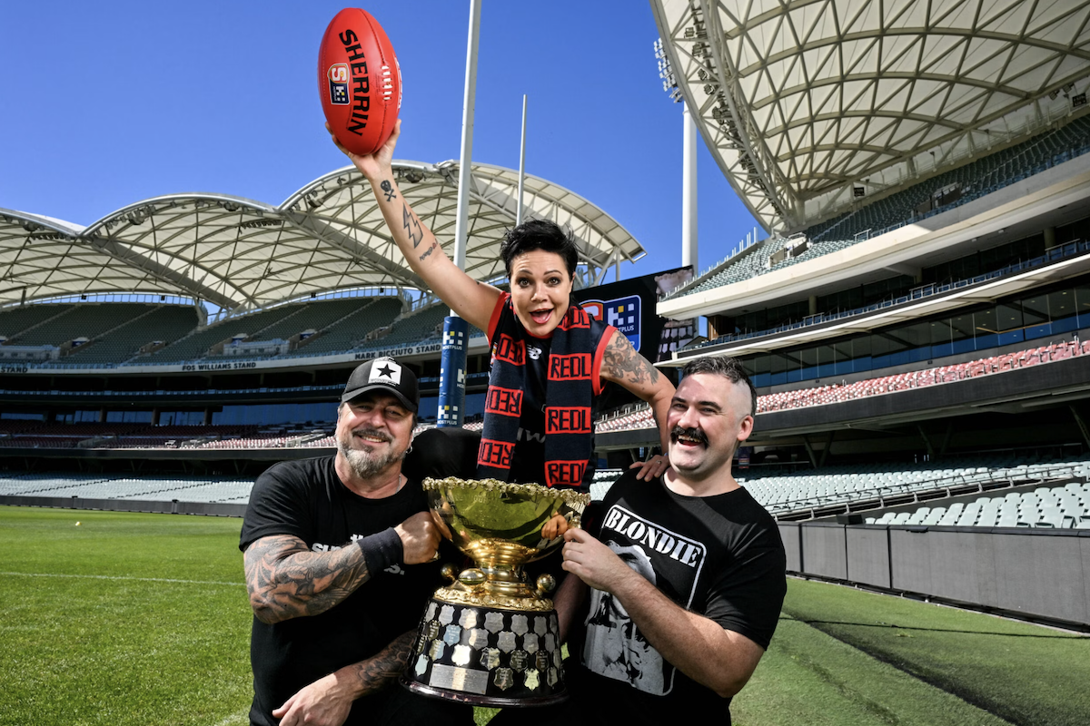 Australian rock band The Superjesus posing with a trophy and football at Adelaide Oval stadium.